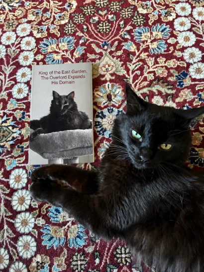 Zuzu beside a printed copy of King of the East Garden, The Overlord Expands His Domain